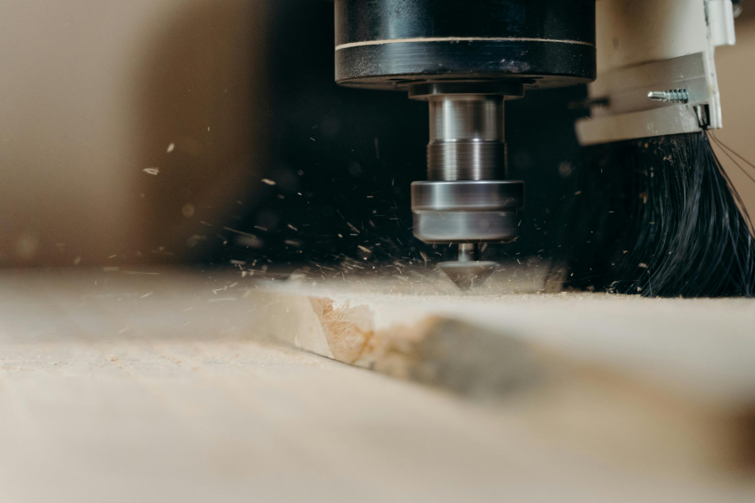 CNC machine in action, precisely cutting a wooden panel with sawdust flying.